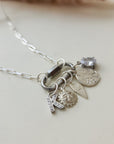 Silver necklace with various charms on a light background