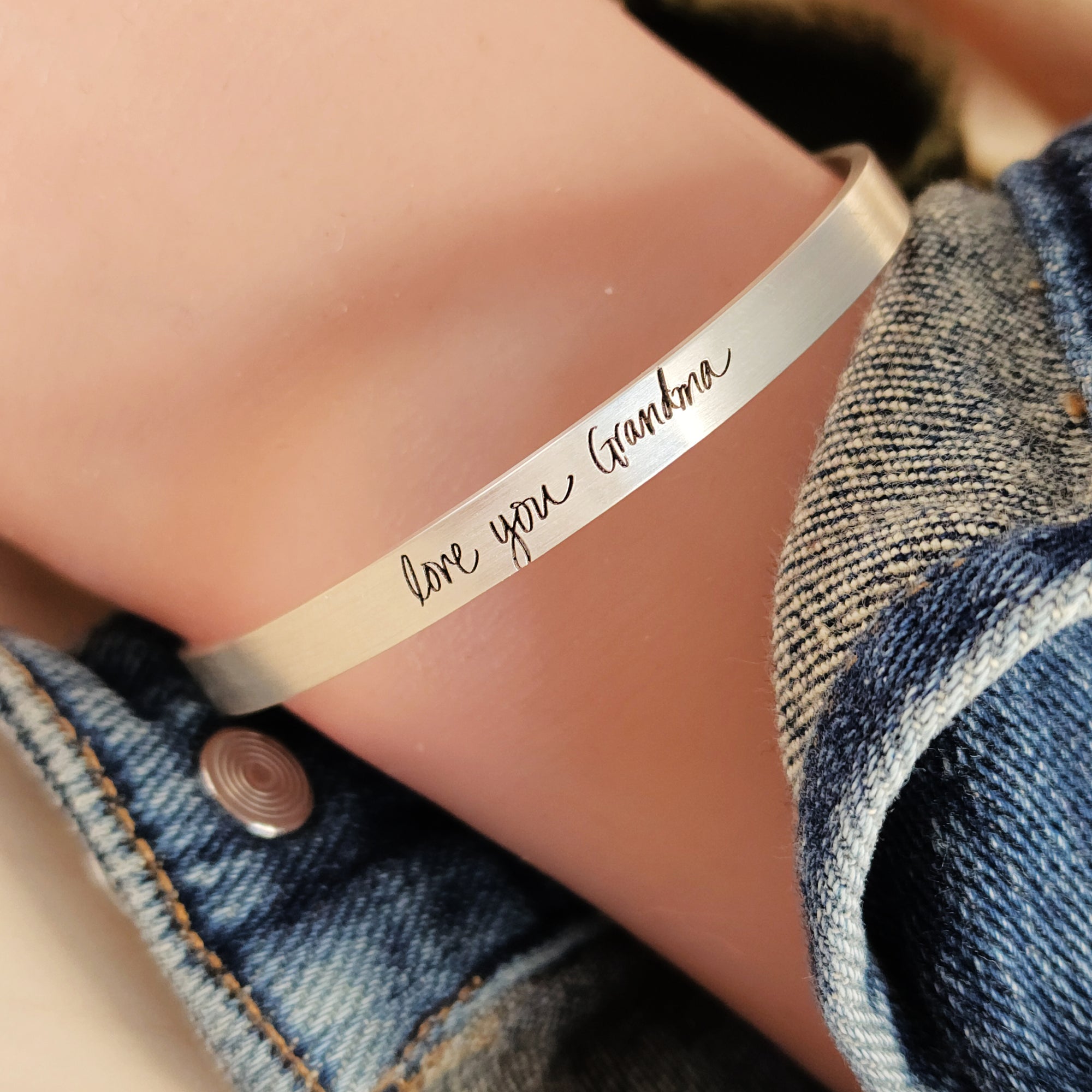 silver cuff bracelet on arm stating love you grandma