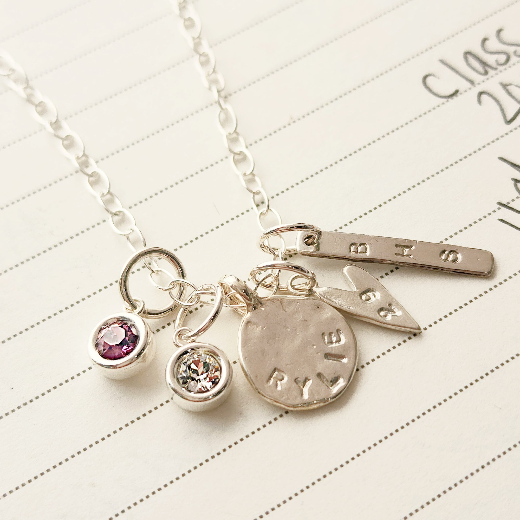 Silver necklace with charms on a lined paper background