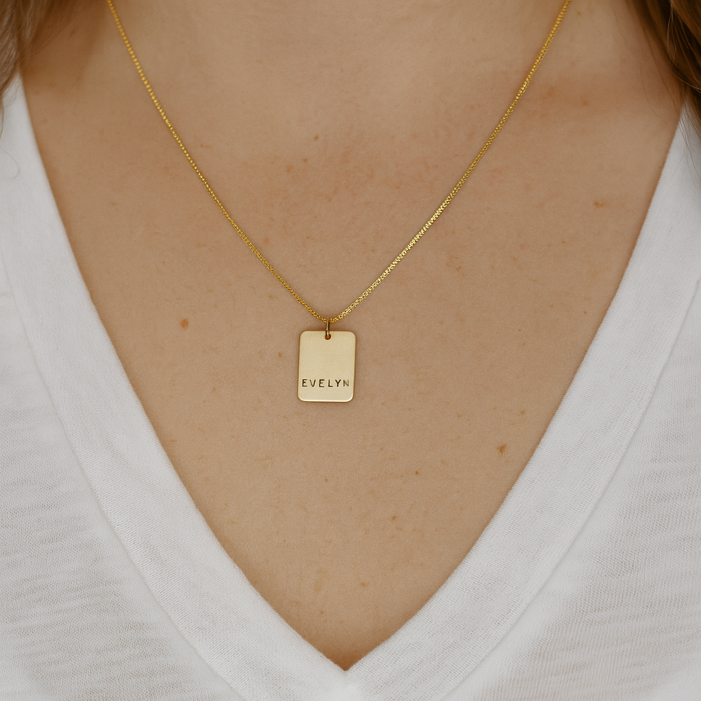 Gold necklace with a tag worn by a person on a white background