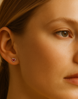 Close-up of a woman wearing heart-shaped earrings with a neutral background
