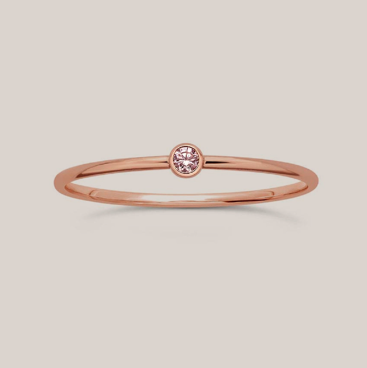 A simple band ring with a single pink gemstone, October birthstone, set in a gold-filled band.
