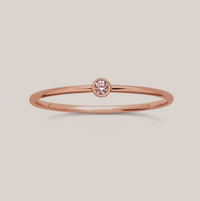 A simple band ring with a single pink gemstone, October birthstone, set in a gold-filled band.