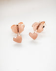 A pair of rose gold heart stud earrings on a white background.