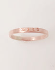 A rose gold-colored stacking name ring with the name 'nico' hand-stamped on it.