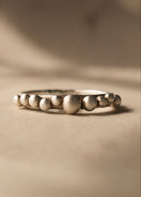 Silver ring with bead-like design on a beige background