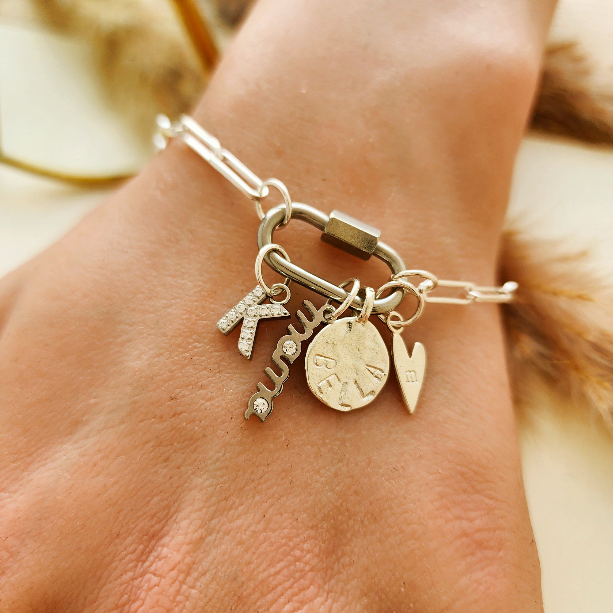 Silver bracelet with charms on a wrist against a blurred background