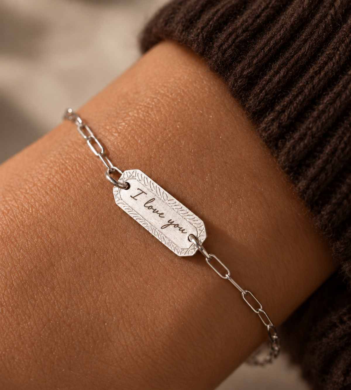 engraved "I love you' paperclip bracelet on wrist with brown sweater