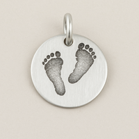 Silver pendant with footprints on a beige background