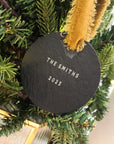 Round slate ornament with 'The Smiths 2025' text on a Christmas tree.