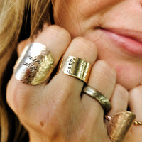 Close-up of a hand wearing multiple gold rings with visible branding.