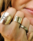 Close-up of a hand wearing multiple gold rings with visible branding.
