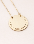 Gold necklace with engraved names on a light pink background