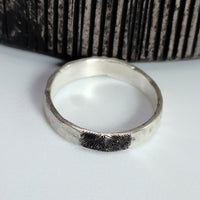 Silver ring with fingerprint design on a white surface