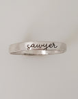 A silver stacking ring with the name 'sawyer' engraved on it, displayed against a white background.