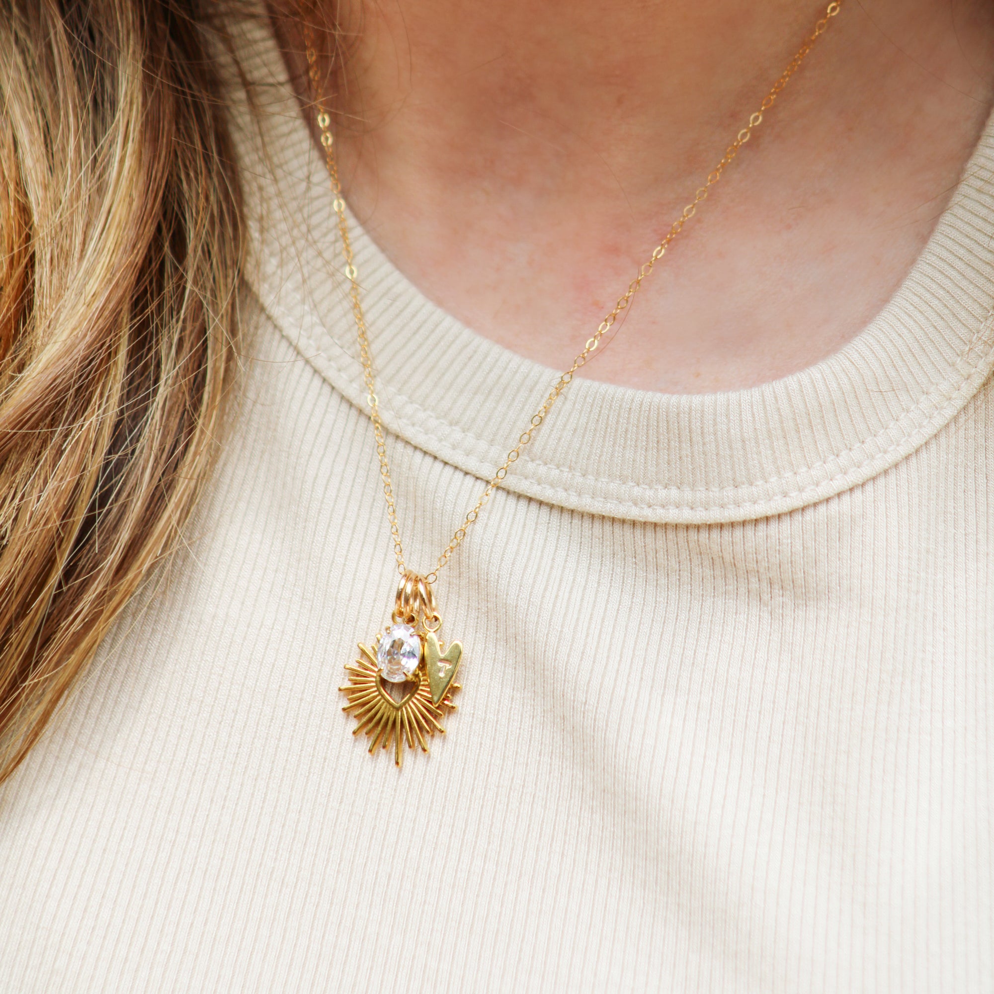 Gold necklace with a pendant worn by a person on a beige background
