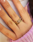 Close-up of a hand wearing two gold rings with a blurred background
