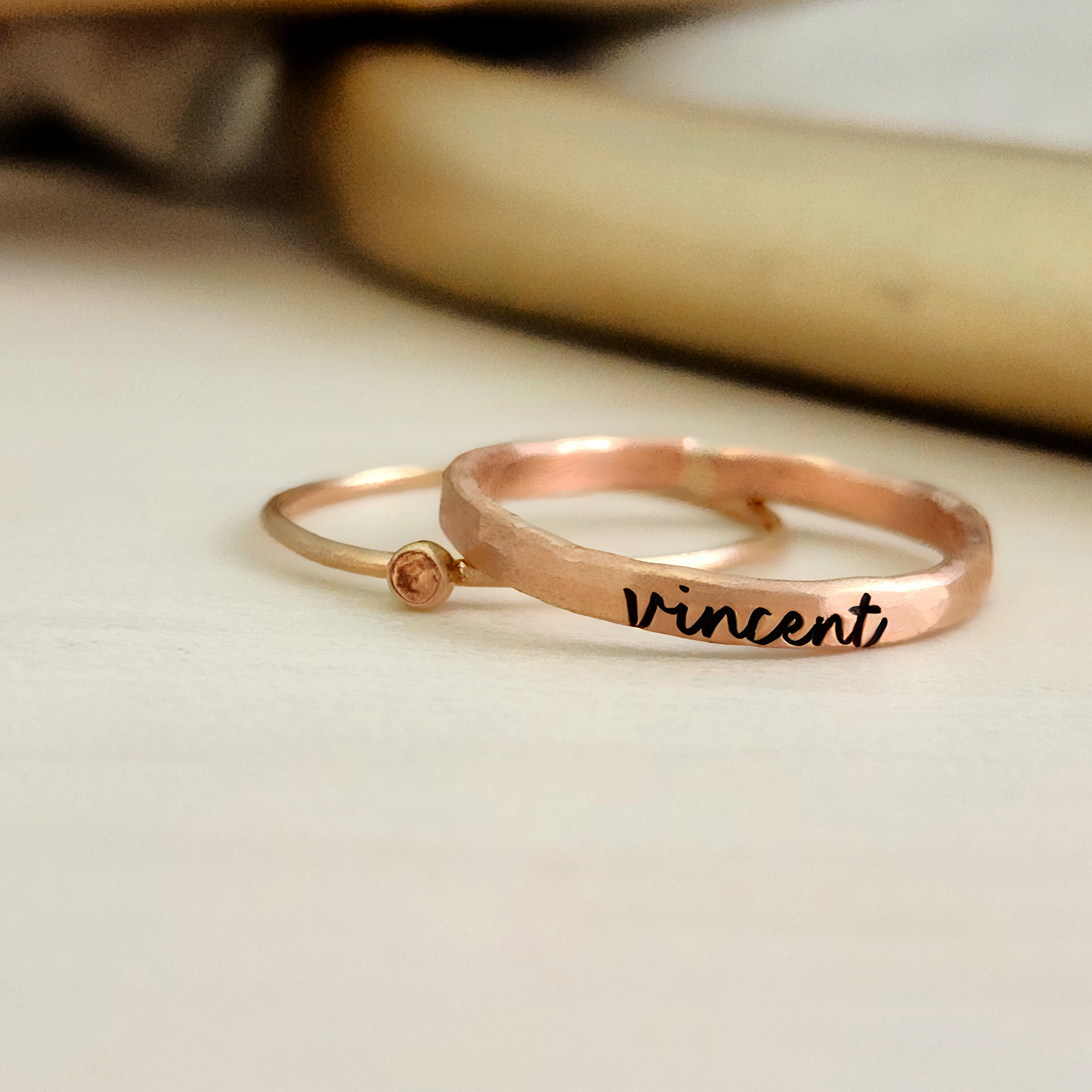 A photo showing a gold-colored ring with the name 'Charlie' engraved on it, worn on a person's finger.
