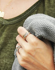 A silver, gold, and rose gold ring stacked on a finger