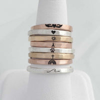 Stacking custom ring set in sterling silver, fine silver, and 14K gold filled with engraved symbols including wings, heart, sun, ribbon, paw print, cross, rainbow, and wave designs